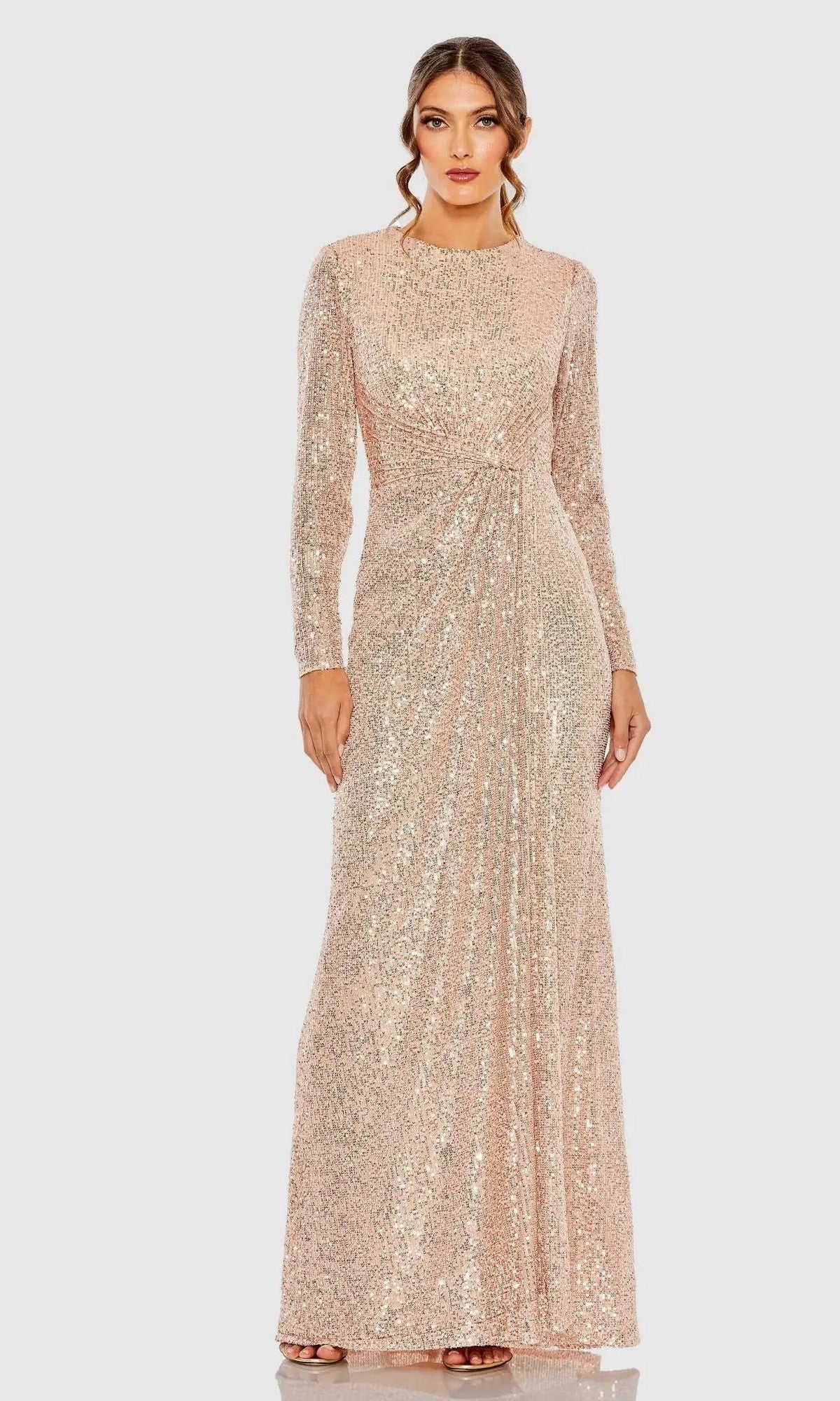 A woman models the Mac Duggal 11659 Long Sleeve Sequin Formal Dress in rose gold, posing against a plain light background.